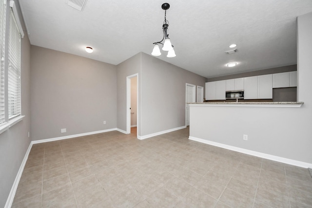 kitchen with decorative light fixtures, kitchen peninsula, and white cabinets