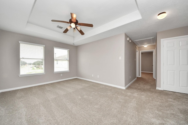 spare room featuring light colored carpet, ceiling fan, and a tray ceiling