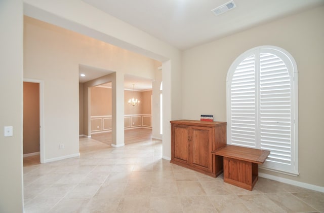 spare room with a chandelier and light tile patterned floors