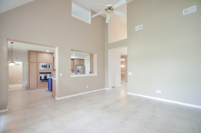 unfurnished living room featuring a high ceiling, ceiling fan with notable chandelier, and light tile patterned floors