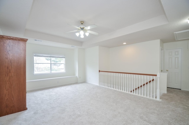 carpeted empty room featuring a tray ceiling and ceiling fan