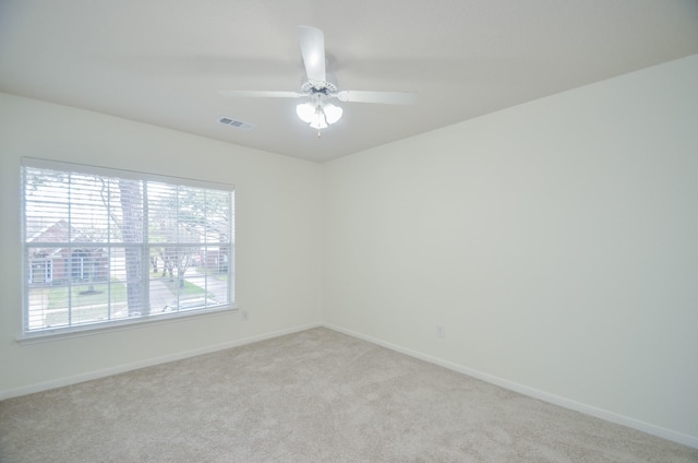 carpeted spare room featuring a wealth of natural light and ceiling fan