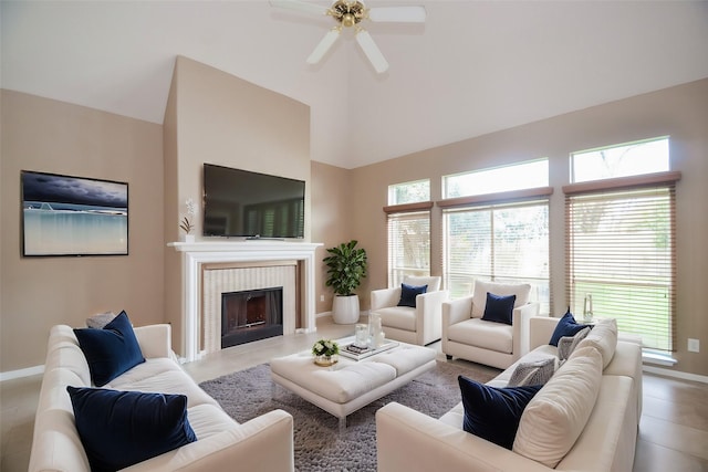 living room with a tiled fireplace, a towering ceiling, light tile patterned floors, and ceiling fan