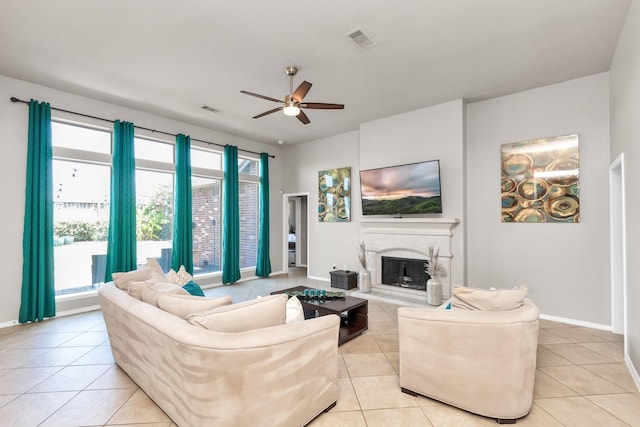 tiled living room with a high end fireplace and ceiling fan