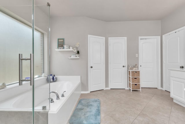 bathroom featuring tile patterned flooring and a relaxing tiled tub