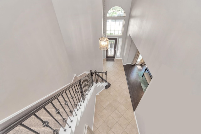 stairs with tile patterned flooring and a towering ceiling