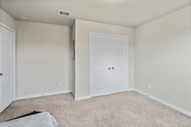 unfurnished bedroom with light carpet, a textured ceiling, and a closet