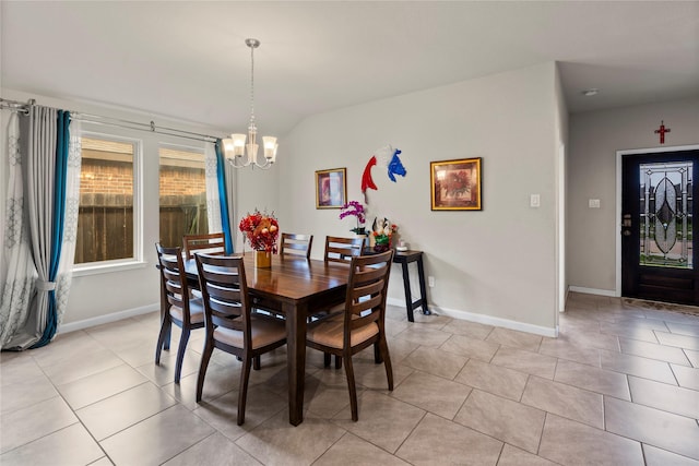 tiled dining area featuring an inviting chandelier and vaulted ceiling