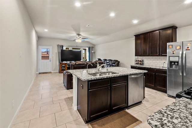 kitchen with sink, stainless steel appliances, dark brown cabinetry, an island with sink, and decorative backsplash