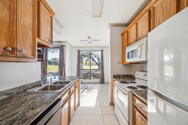 kitchen featuring sink, light tile patterned floors, white appliances, ceiling fan, and a textured ceiling