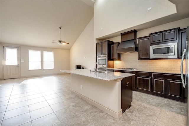 kitchen with sink, appliances with stainless steel finishes, a kitchen island with sink, decorative backsplash, and custom exhaust hood