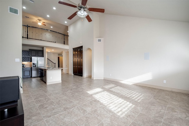 unfurnished living room featuring ceiling fan, high vaulted ceiling, sink, and light tile patterned floors