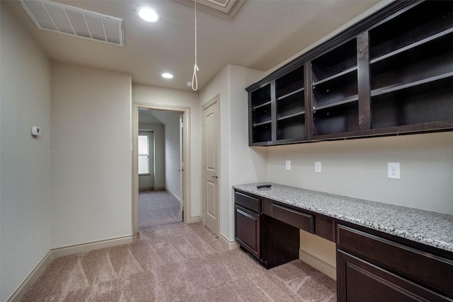 unfurnished office featuring built in desk and light colored carpet