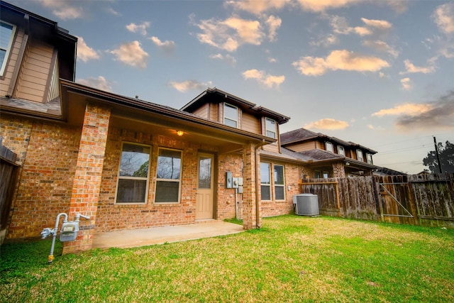 back of house with central AC unit, a patio area, and a lawn