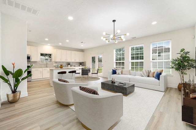 living room with an inviting chandelier and light wood-type flooring