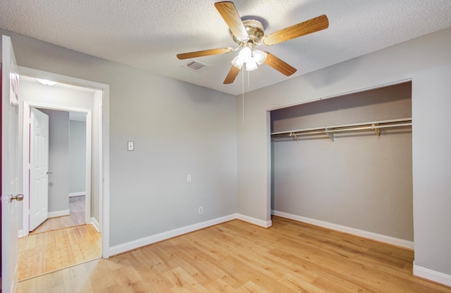 unfurnished bedroom with wood finished floors, visible vents, a ceiling fan, a closet, and baseboards