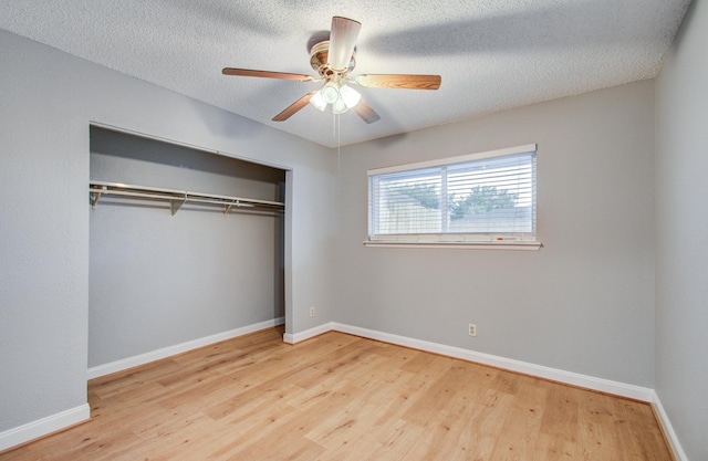 unfurnished bedroom featuring a textured ceiling, wood finished floors, a closet, and baseboards