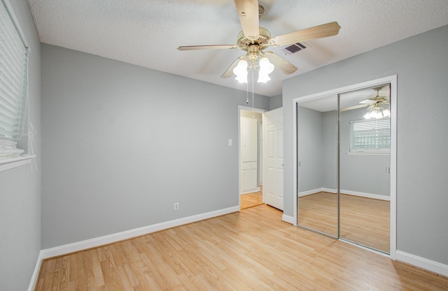 unfurnished bedroom featuring visible vents, baseboards, wood finished floors, a closet, and ceiling fan