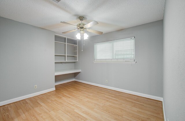spare room featuring baseboards, a ceiling fan, wood finished floors, and a textured ceiling