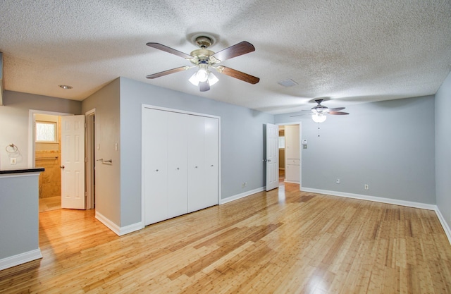 unfurnished bedroom with light wood-type flooring, baseboards, a textured ceiling, and a closet