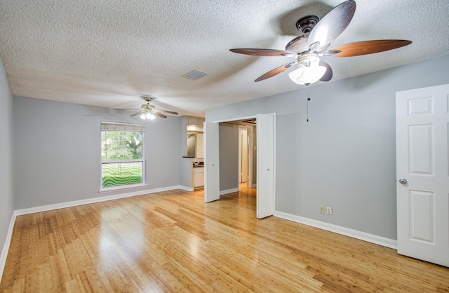unfurnished room featuring a ceiling fan, visible vents, a textured ceiling, and light wood-style flooring