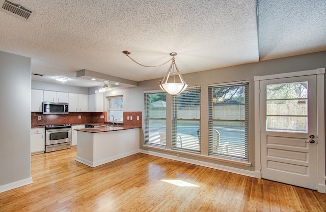 kitchen with light wood finished floors, stainless steel appliances, a sink, visible vents, and white cabinetry