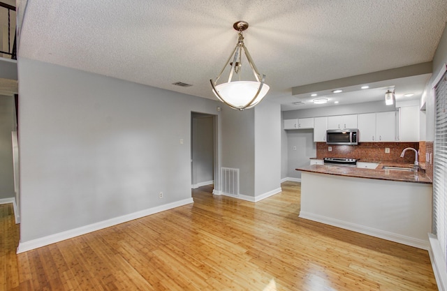 kitchen with white cabinets, stainless steel appliances, backsplash, visible vents, and a sink