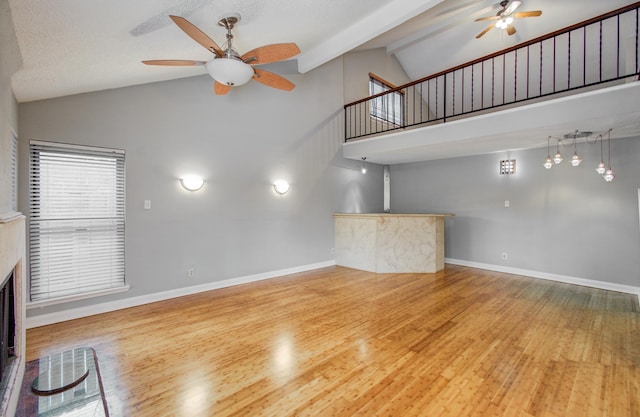 unfurnished living room featuring high vaulted ceiling, a ceiling fan, wood finished floors, and bar area