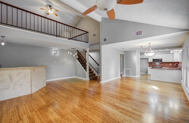 unfurnished living room featuring visible vents, stairs, and ceiling fan