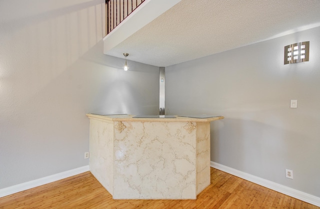 bar with baseboards, a dry bar, wood finished floors, and a textured ceiling