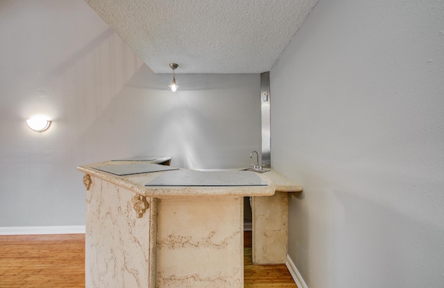 bar with light wood-style floors, a textured ceiling, baseboards, and indoor wet bar