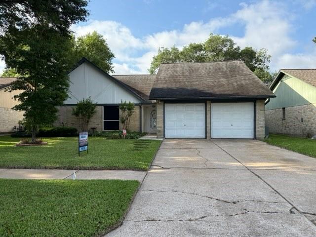 view of front of house with driveway, a garage, brick siding, a shingled roof, and a front yard