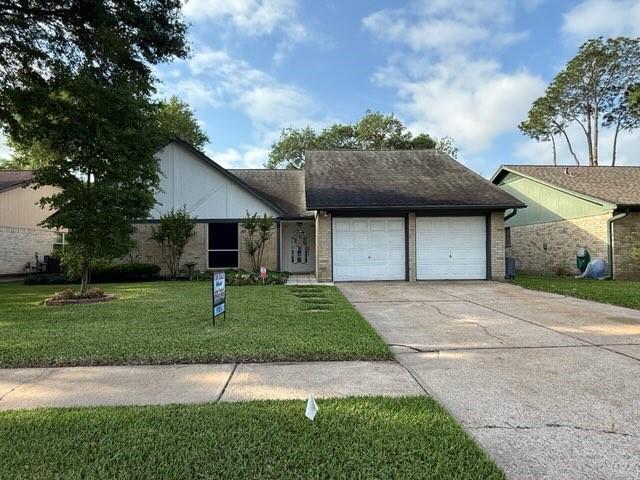 view of front of house featuring an attached garage, a front lawn, and concrete driveway