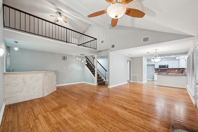 22403 Elsinore Dr, Katy, TX 77450 - unfurnished living room featuring a ceiling fan, stairway, high vaulted ceiling, and light wood-style flooring