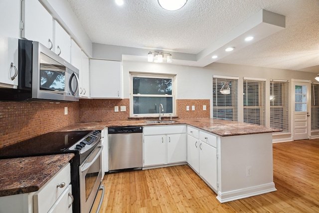 22403 Elsinore Dr, Katy, TX 77450 - kitchen with appliances with stainless steel finishes, recessed lighting, a peninsula, light wood finished floors, and a textured ceiling