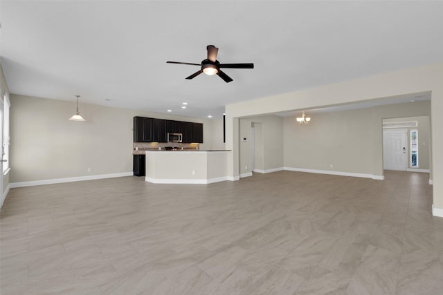 unfurnished living room featuring ceiling fan with notable chandelier