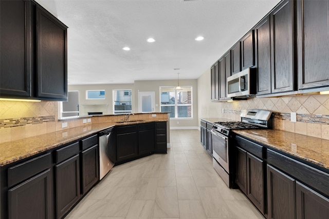 kitchen featuring sink, light stone countertops, stainless steel appliances, and pendant lighting