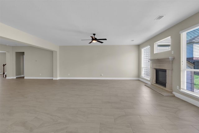 unfurnished living room with ceiling fan and a tile fireplace