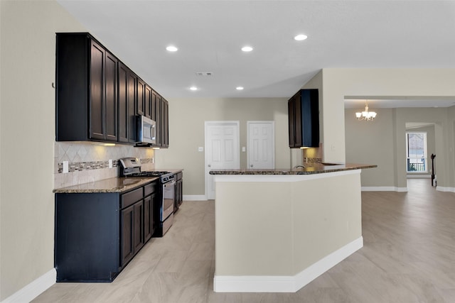 kitchen featuring appliances with stainless steel finishes, decorative backsplash, pendant lighting, and dark stone countertops