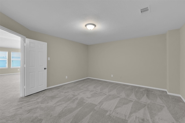 spare room with a textured ceiling and light colored carpet