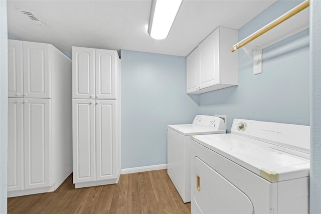 laundry room featuring cabinets, washer and dryer, and light wood-type flooring