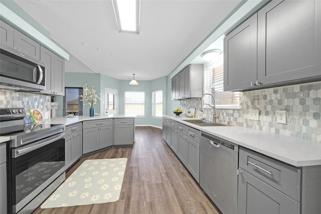 kitchen with sink, dark wood-type flooring, gray cabinetry, stainless steel appliances, and kitchen peninsula