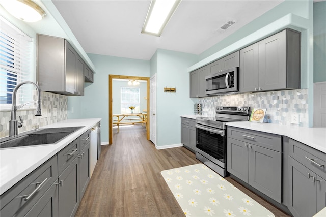 kitchen featuring stainless steel appliances, dark hardwood / wood-style flooring, gray cabinets, and sink