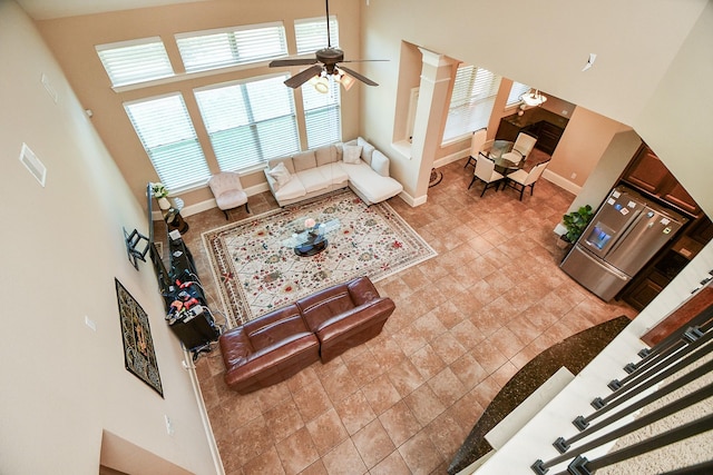 living room featuring a high ceiling, baseboards, and ceiling fan