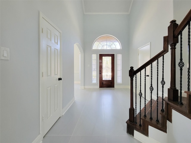 foyer entrance featuring a high ceiling, crown molding, and light tile patterned flooring