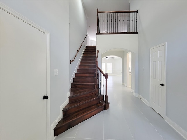 stairs with tile patterned flooring and a towering ceiling