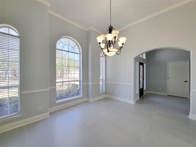 spare room with ornamental molding, light tile patterned floors, plenty of natural light, and a chandelier