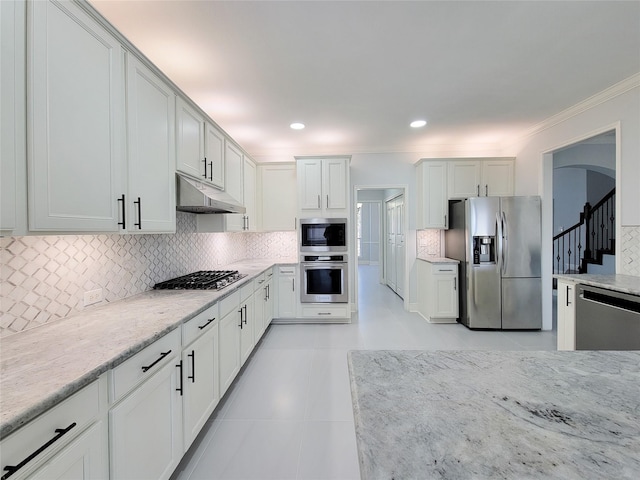 kitchen featuring white cabinetry, stainless steel appliances, light stone countertops, and tasteful backsplash