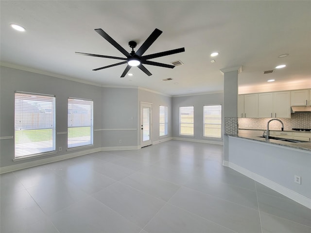 unfurnished living room with ceiling fan, ornamental molding, sink, and light tile patterned floors