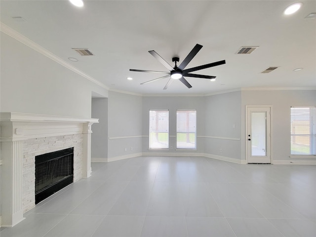 unfurnished living room featuring ceiling fan, a stone fireplace, crown molding, and a wealth of natural light